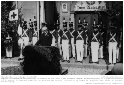 Mitglieder der Bürgerwehr der Heimatvereinigung "Oald Bensem" vor dem Rathaus auf dem Bensheimer Marktplatz während der Eröffnung des 3. Bergsträßer Winzerfestes 1931 in Bensheim. Am Rednerpult Joseph Stoll, der Vorsitzende des Bensheimer Verkehrsvereins und Initiator der Winzerfestes sowie Gründer der Bensheimer Heimatvereinigung.; Kennung: NLJS_Fotoalbum_Winzerfestumzug_1932_0116 Mitglieder der Bürgerwehr der Heimatvereinigung "Oald Bensem" vor dem Rathaus auf dem Bensheimer Marktplatz während der Eröffnung des 3. Bergsträßer Winzerfestes 1931 in Bensheim. Am Rednerpult Joseph Stoll, der Vorsitzende des Bensheimer Verkehrsvereins und Initiator der Winzerfestes sowie Gründer der Bensheimer Heimatvereinigung.; Kennung: Album_Oald_Bensem_und_Buergerwehr_Bild_0116