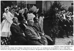 Einweihung des Josef Stoll-Platzes am 5. Oktober 1957. Blick auf die Ehrengäste (v.l.n.r): Roth, Hess, Schachner und Bürgermeister Kilian, im Hintergrund links: Margarete Stoll, Egon Stoll-Berberich, Maria Stoll-Berberich, Jürgen Stoll-Berberich; stehend dahinter die Biedermeiergruppe der Heimatvereinigung Oald Bensem.; Kennung: NLJS_00073b