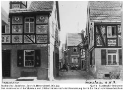 Bensheimer Hasenviertel, Mittlere Hasengasse 15 um 1935. Das Ergebnis der Verschönerungsarbeiten durch die Maler- und Gewerbeschule. Spruch auf der Hauswand links: Is an de Stiwwel woas bassiert, hier wärrnse billig reperiert. Spruch auf dem Haus rechts: Es häwwe mol in dem Gevert sich frieher Hoase als veerrt. Quelle: Stadtarchiv Bensheim.