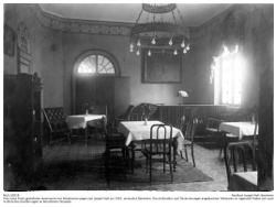 Foto eines frisch gestalteten Innenraums mit Wandverzierungen von Joseph Stoll um 1910, vermutlich Bensheim. Die als Bordüre und Türverzierungen angebrachten Malereien im Jugendstil finden sich auch in ähnlichen Ausführungen an Bensheimer Fassaden.